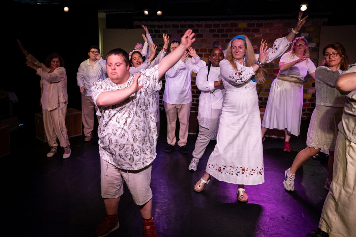 Artiesten van Fenix Theatermakers die bezig zijn met een dans optreden. Ze dragen witte kleding.